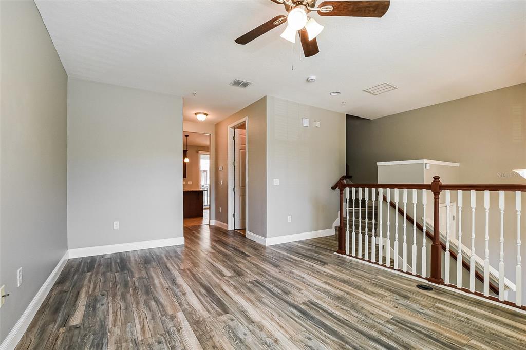 A room with wood-look flooring, a ceiling fan, and a staircase with a wooden railing — 1384 MILL STREAM LANE, WINTER SPRINGS, FL