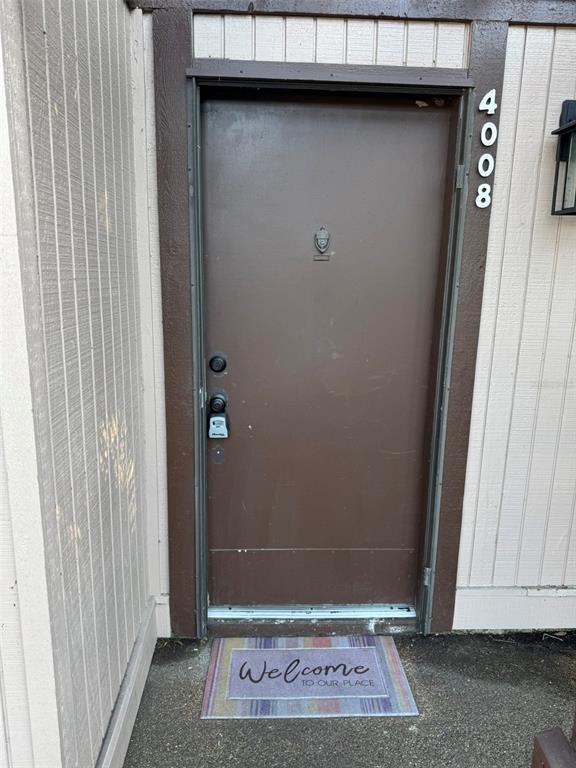 A brown front door with a lockbox and a welcome mat sits in a beige wall — 4008 MURIEL PLACE UNIT 1, TAMPA, FL