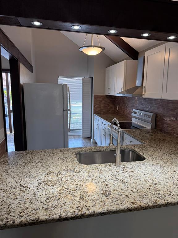 A kitchen features granite countertops, white cabinetry, a stainless steel sink, and a tiled backsplash — 4008 MURIEL PLACE UNIT 1, TAMPA, FL
