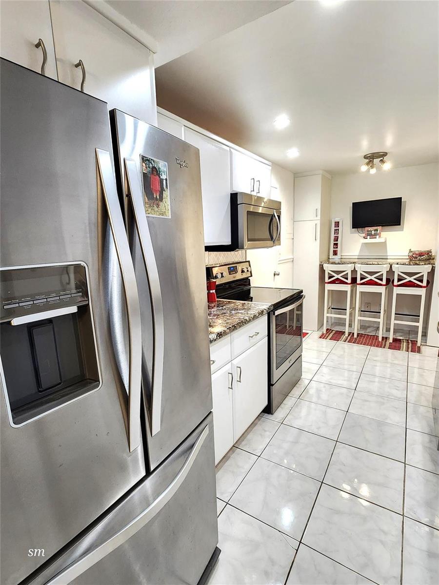 A kitchen features white cabinets, stainless steel appliances, granite countertops, and a breakfast bar area — 4400 Hillcrest Drive # 404, Hollywood FL 33021, HOLLYWOOD, FL