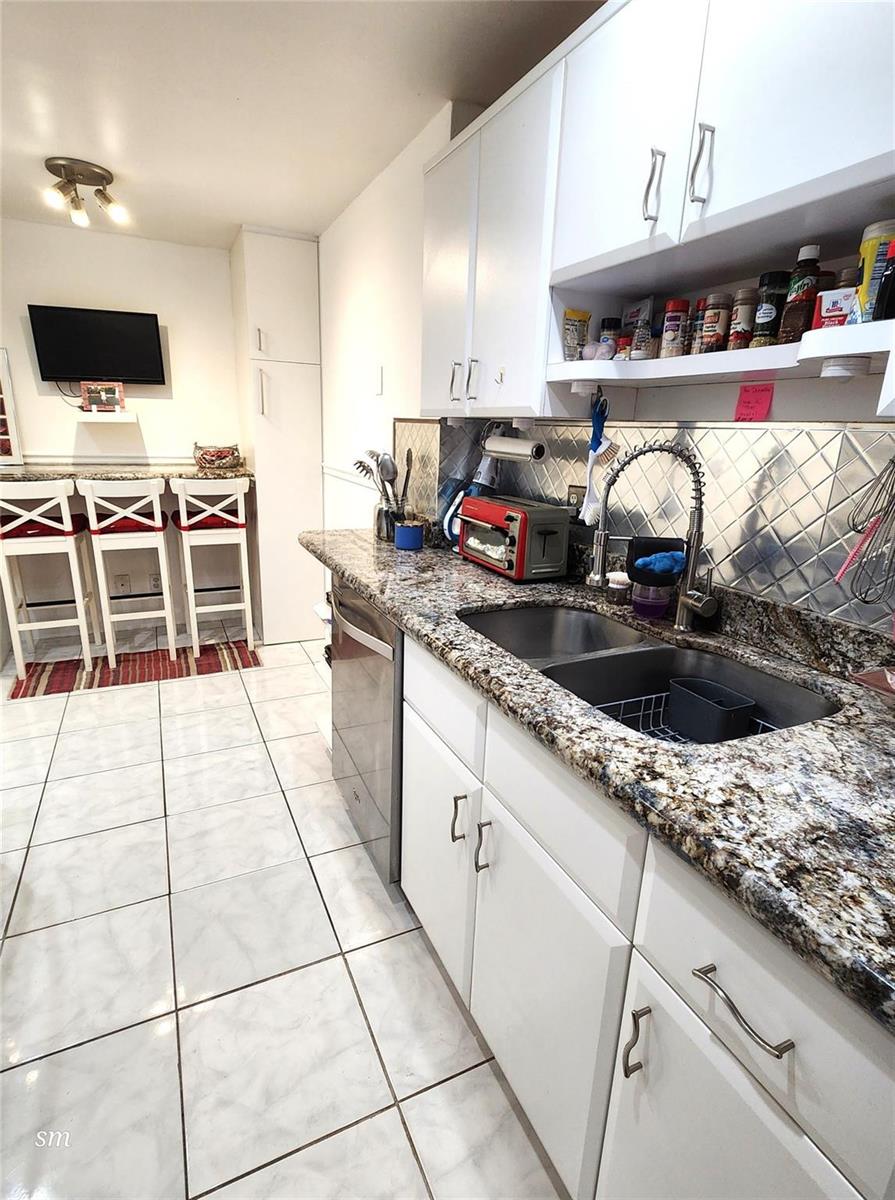 A kitchen features white cabinets, granite countertops, a stainless steel sink, and a breakfast bar — 4400 Hillcrest Drive # 404, Hollywood FL 33021, HOLLYWOOD, FL