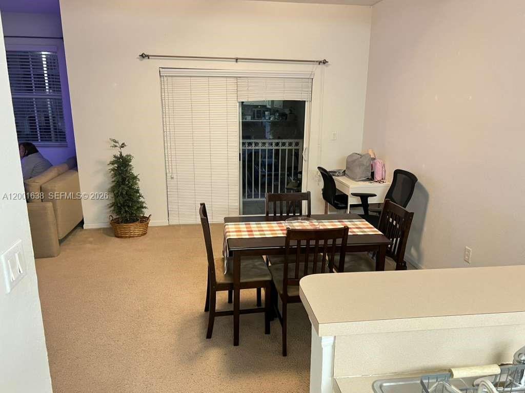 A living room with beige carpet, a sofa, a television, and a balcony with chairs — 11102 NW 83rd St # 217, Doral FL 33178, DORAL, FL
