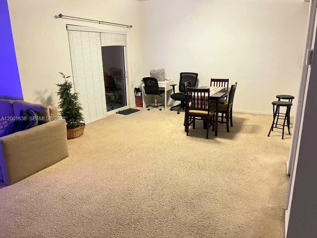 A living room features beige carpet, a sofa, a dining set, and a sliding glass door — 11102 NW 83rd St # 217, Doral FL 33178, DORAL, FL