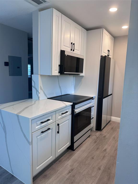A kitchen features white shaker cabinets, marble-patterned quartz countertops, and black stainless steel appliances — 2780 OCEAN SHORE BOULEVARD UNIT 8S, ORMOND BEACH, FL
