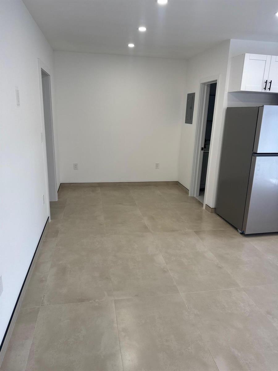 A kitchen area with light-colored tile flooring, white walls, and a stainless steel refrigerator — 1235 Normandy Drive # 10, Miami Beach FL 33141, MIAMI BEACH, FL