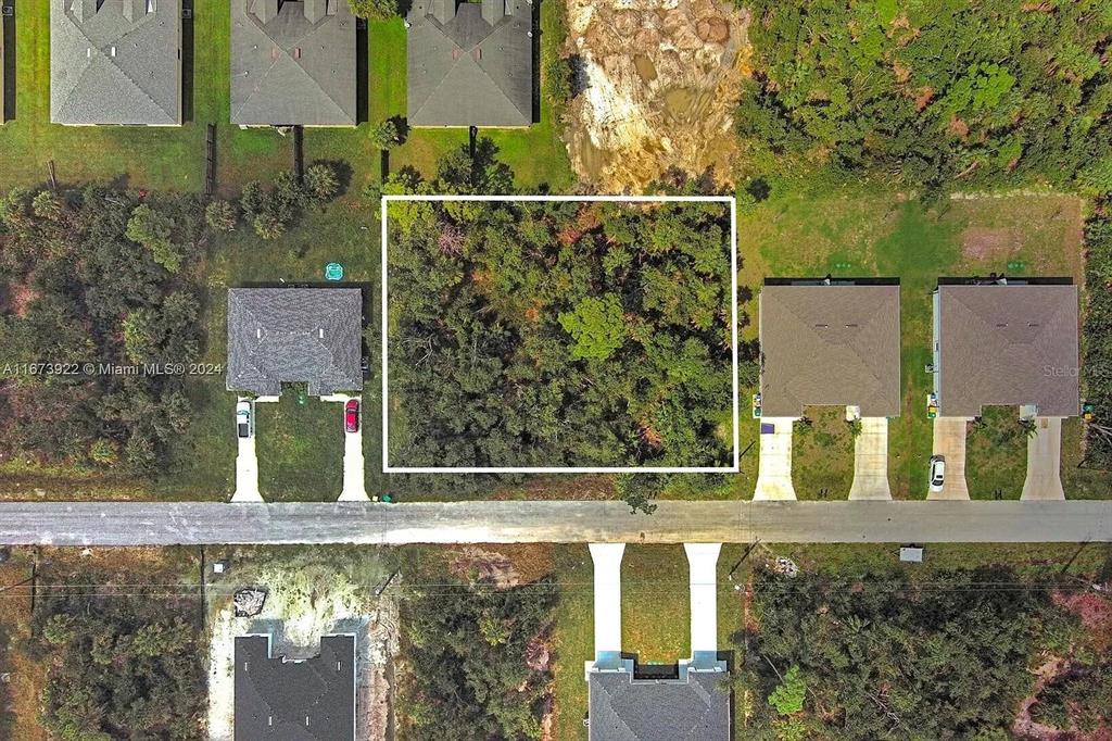 This aerial view shows a vacant, wooded residential lot outlined in white between two houses — 145 LOFTIN STREET, PORT CHARLOTTE, FL