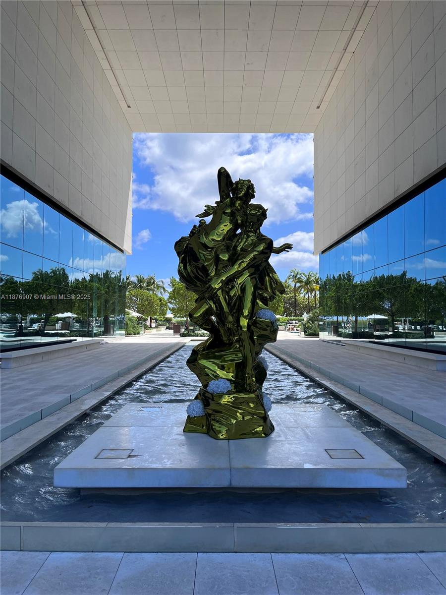 A large, reflective green sculpture stands in a water feature between two modern glass buildings — 10201 Collins Ave # 301, Bal Harbour FL 33154, BAL HARBOUR, FL