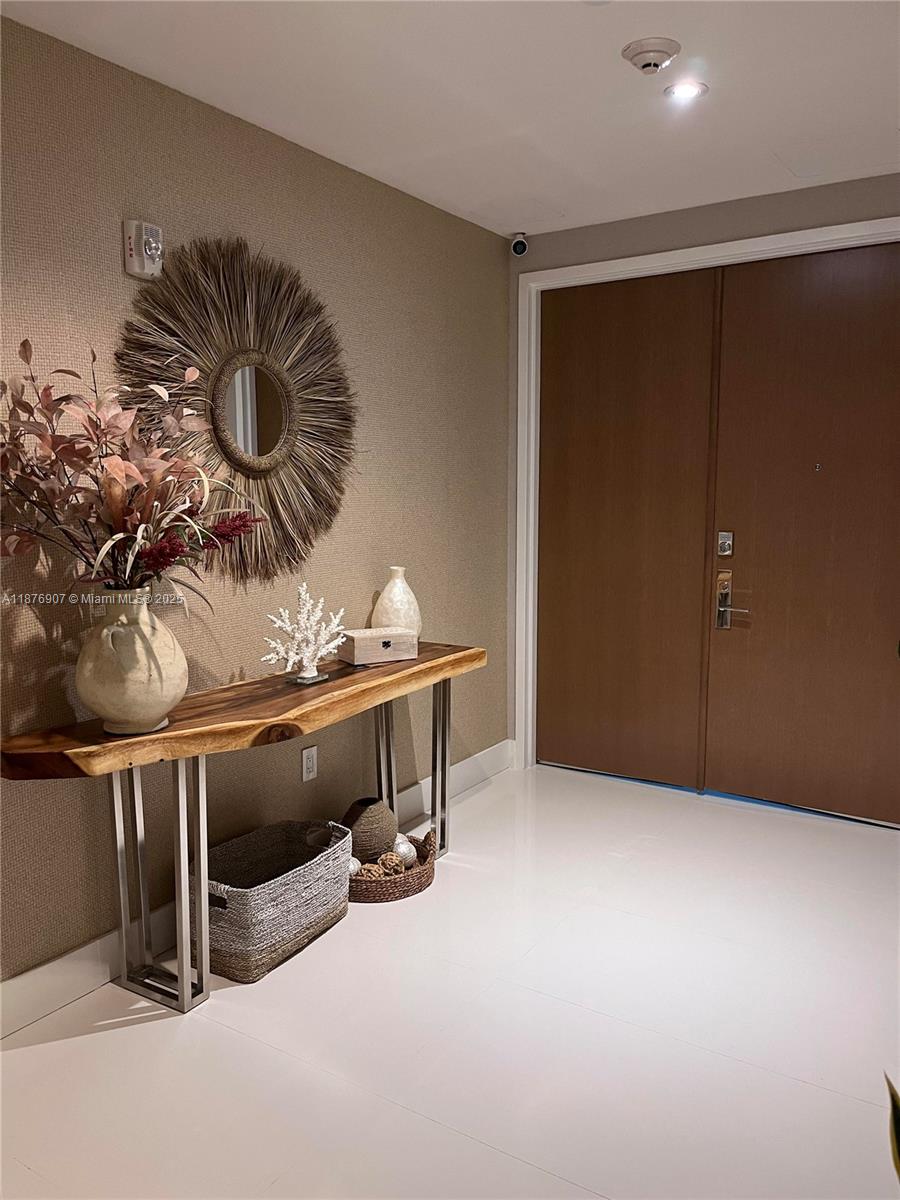 A modern entryway features a live-edge wood console table, a textured mirror, and double doors — 10201 Collins Ave # 301, Bal Harbour FL 33154, BAL HARBOUR, FL