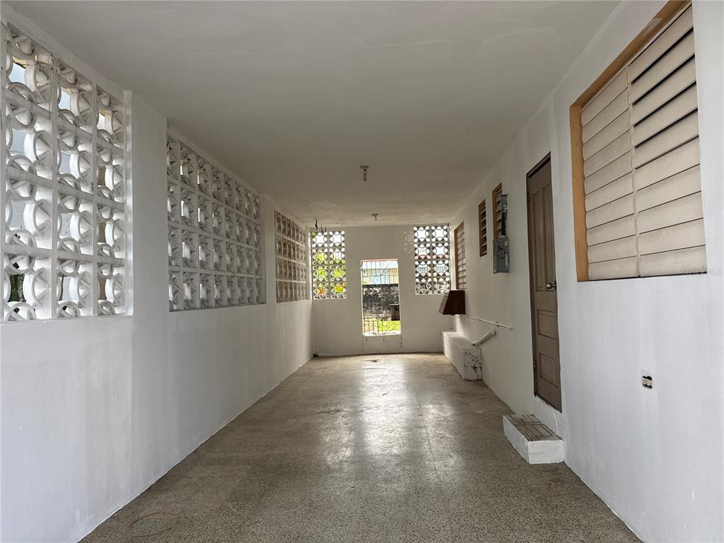 A long, covered carport features white walls, decorative breeze blocks, and a concrete floor — 121 CALLE HERMANDAD INTERIOR, GUAYNABO, PR