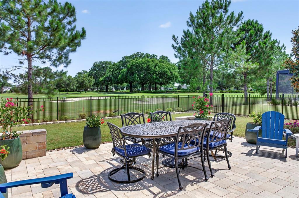 A patio with a metal dining set overlooks a golf course behind a black fence — 5448 NW 35TH LANE ROAD, OCALA, FL