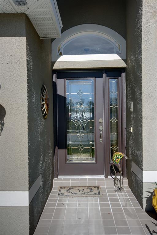 A front entryway features a dark brown door with a glass insert, sidelight, and arched transom — 15825 DURANGO CIRCLE, BROOKSVILLE, FL