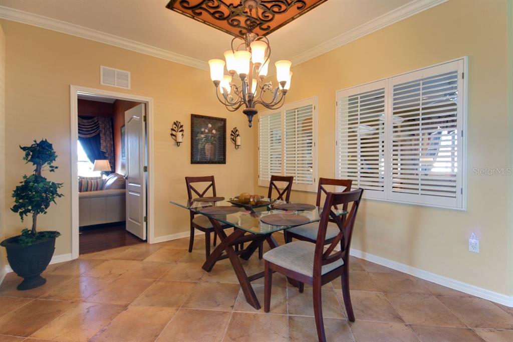 A dining room features a glass-top table, wooden chairs, tile flooring, and a chandelier — 15825 DURANGO CIRCLE, BROOKSVILLE, FL