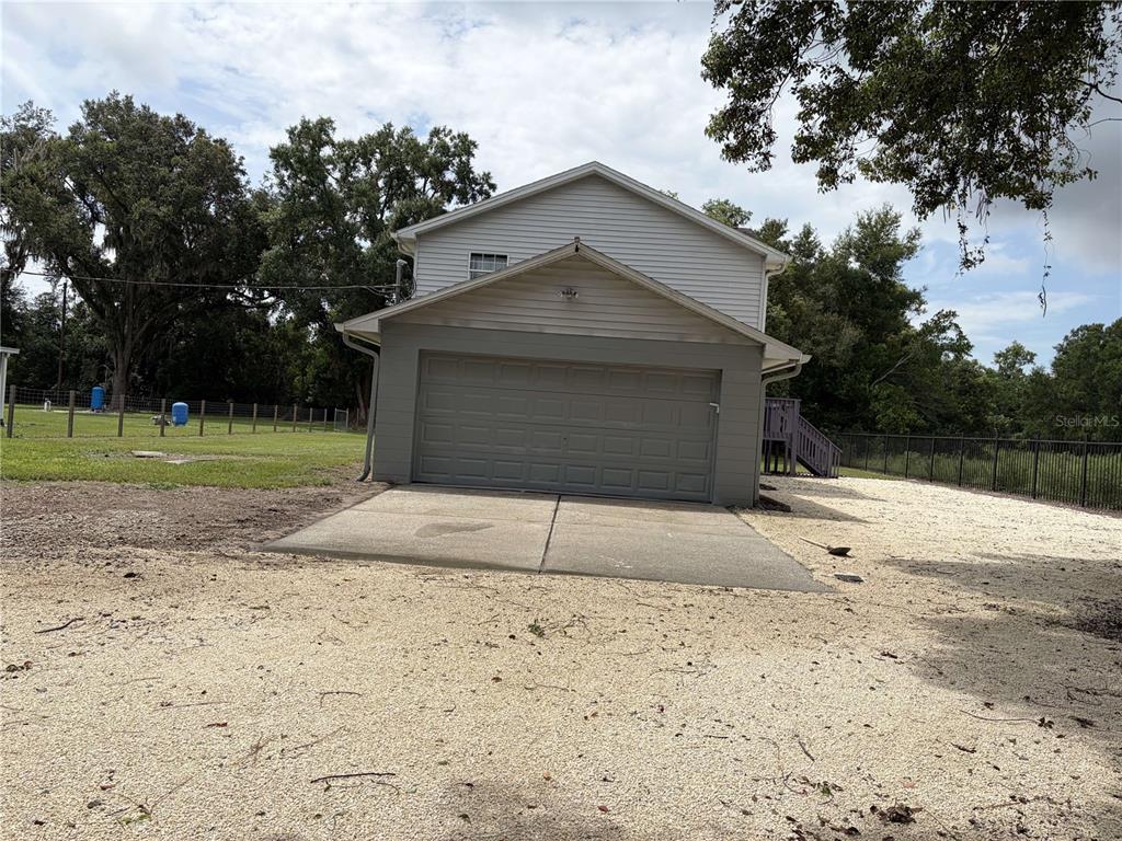 A two-story house with a gray garage door and a gravel driveway — 4706 COATS ROAD, ZEPHYRHILLS, FL