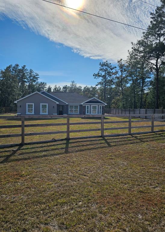 A single-story house with a fenced yard sits in a clearing surrounded by pine trees — 854 FISHER ROAD, OCKLAWAHA, FL