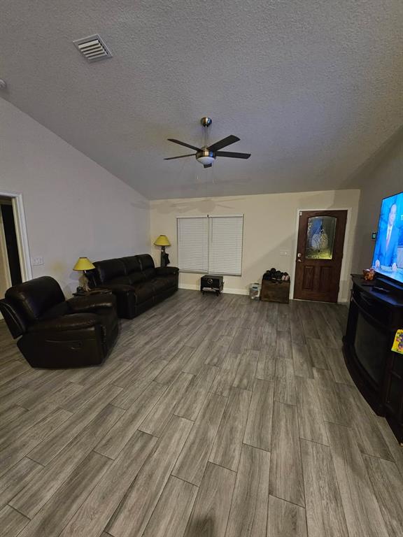 A living room features gray wood-look tile flooring, a ceiling fan, and dark leather furniture — 854 FISHER ROAD, OCKLAWAHA, FL