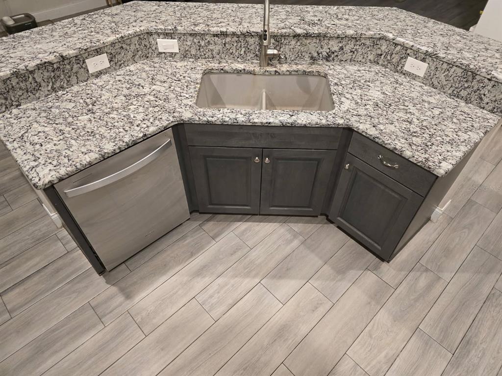 A kitchen island features a stainless steel sink, dark cabinets, and speckled granite countertops — 854 FISHER ROAD, OCKLAWAHA, FL
