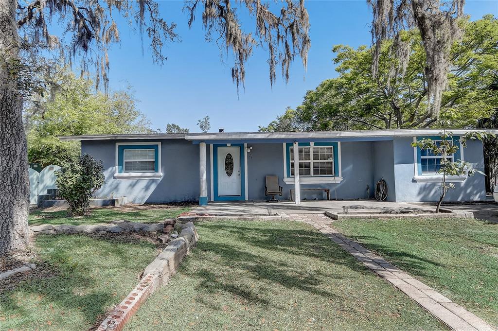 A single-story blue house with a covered front porch and a brick-lined walkway — 243 W MARTIN STREET, APOPKA, FL