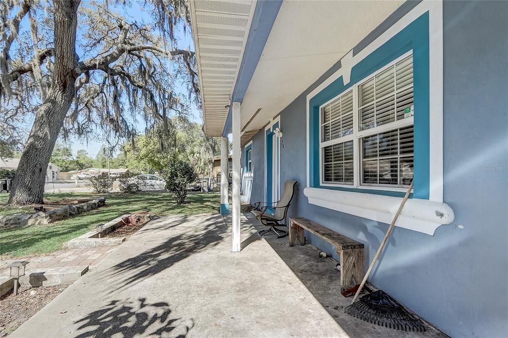 A concrete porch with a wooden bench and a chair sits beside a blue house — 243 W MARTIN STREET, APOPKA, FL