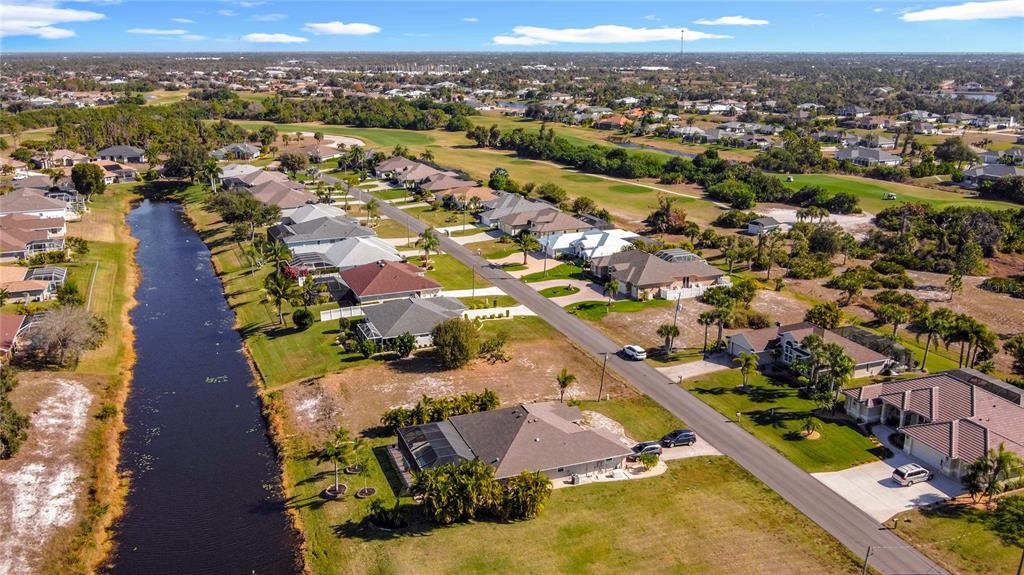 An aerial view shows a suburban neighborhood with houses along a road and a canal — 7 MEDALIST LANE, ROTONDA WEST, FL