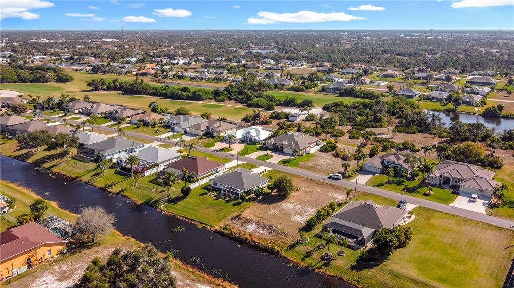 An aerial view shows suburban houses with swimming pools and lawns bordering a canal — 7 MEDALIST LANE, ROTONDA WEST, FL