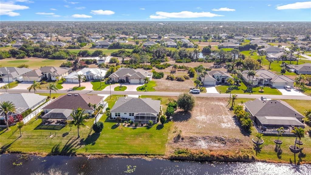An aerial view shows several suburban houses, a vacant lot, and a canal — 7 MEDALIST LANE, ROTONDA WEST, FL
