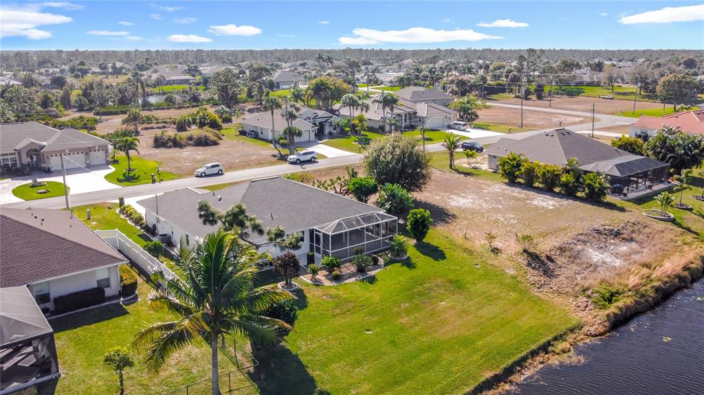 An aerial view shows suburban houses with screened lanais and backyards bordering a canal — 7 MEDALIST LANE, ROTONDA WEST, FL