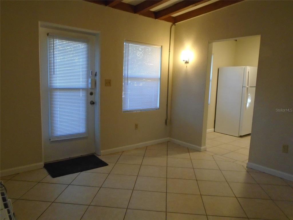A room with tiled floors, a door, a window with blinds, and a kitchen view — 131 LEMON LANE, CASSELBERRY, FL