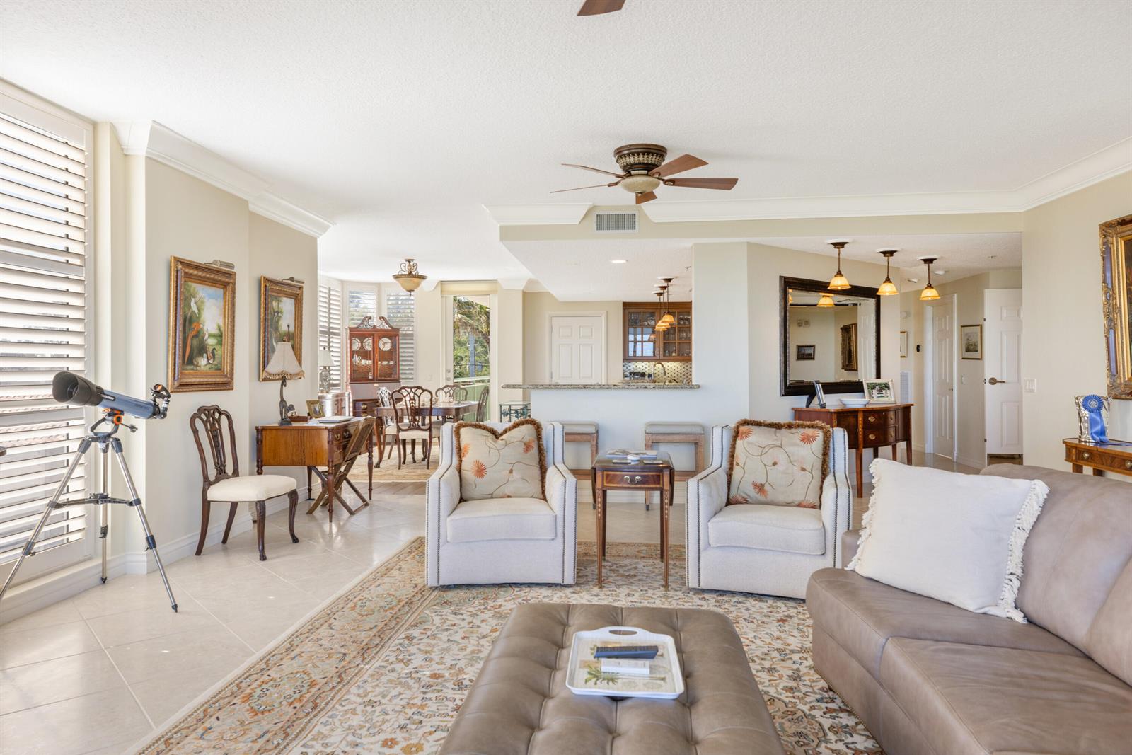 A living room features a telescope, two armchairs, a leather sofa, and an open kitchen — HUTCHINSON ISLAND, FL