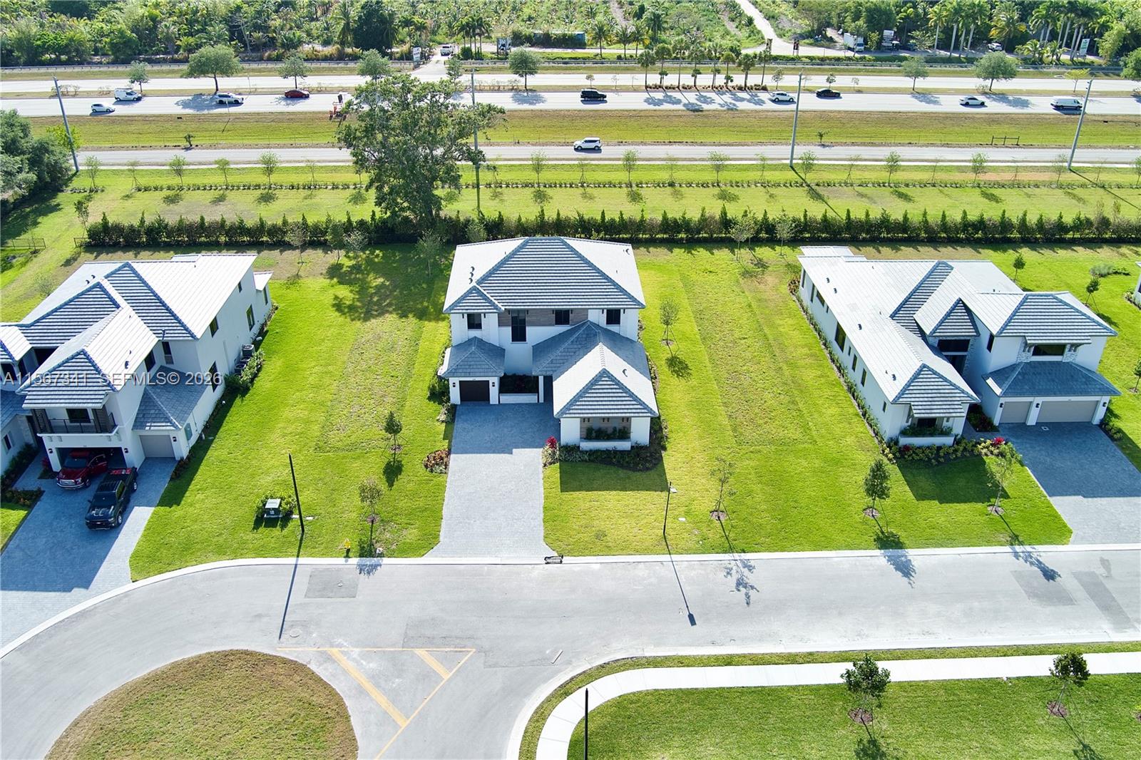An aerial view shows three modern houses with gray roofs and driveways near a highway — 2391 SW 123rd Ter, Davie FL 33325, DAVIE, FL