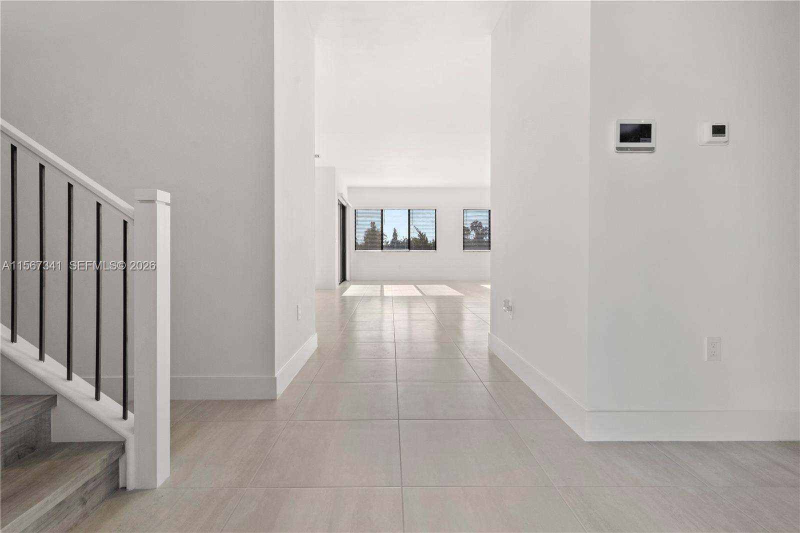 A bright hallway with light tile flooring leads to an open living area with windows — 2391 SW 123rd Ter, Davie FL 33325, DAVIE, FL