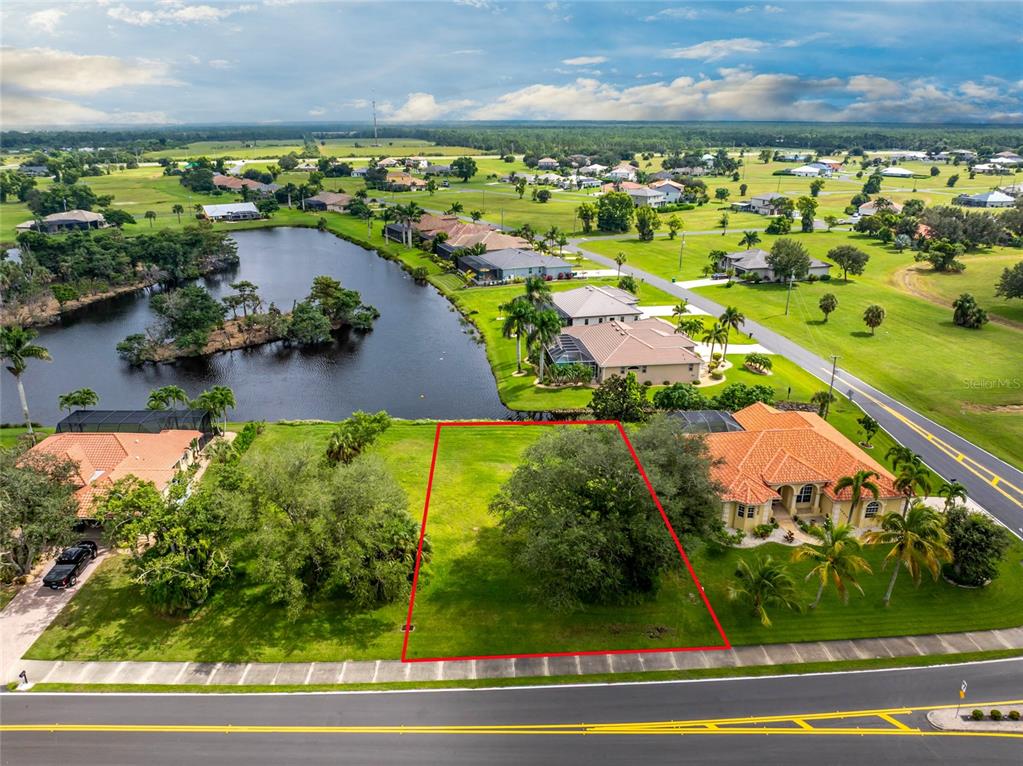 An aerial view shows a vacant residential lot outlined in red between two houses — 17204 CAPE HORN BOULEVARD, PUNTA GORDA, FL