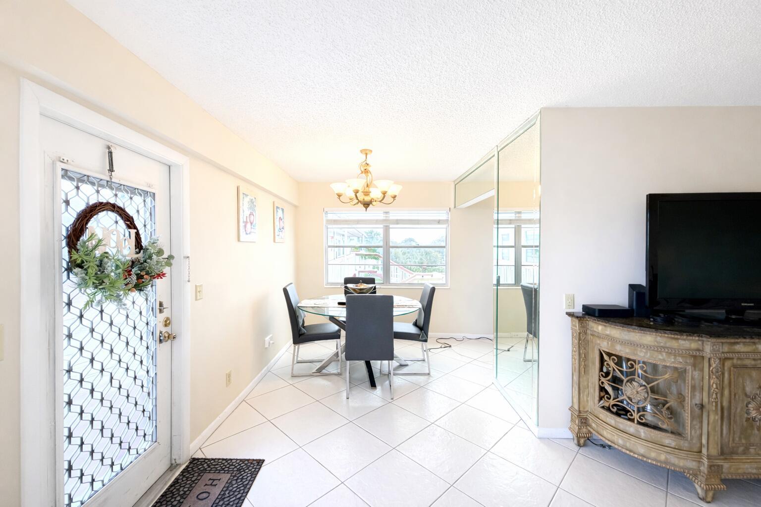 A dining area with tile floors, a glass table, and a mirrored wall — 33 Preston A, Boca Raton FL 33434, BOCA RATON, FL