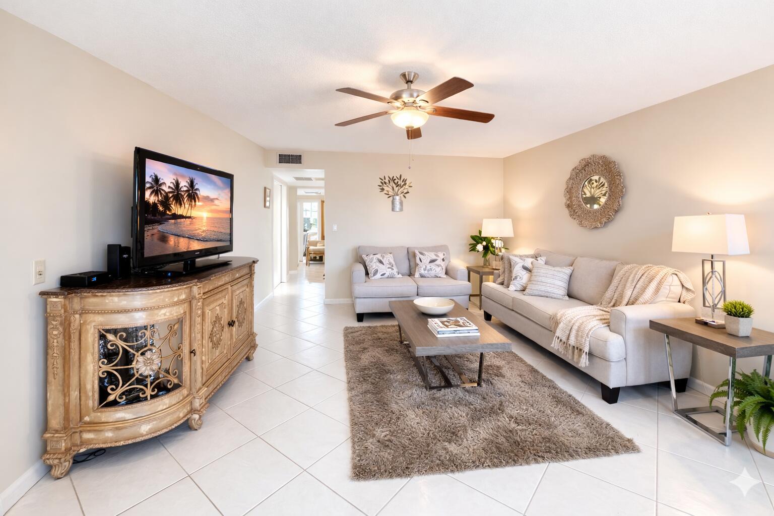 A living room features a television on a decorative cabinet, a sofa, and tile flooring — 33 Preston A, Boca Raton FL 33434, BOCA RATON, FL