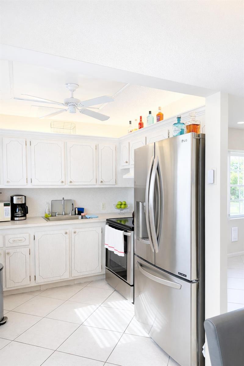 A kitchen features white cabinets, stainless steel appliances, and a ceiling fan — 33 Preston A, Boca Raton FL 33434, BOCA RATON, FL