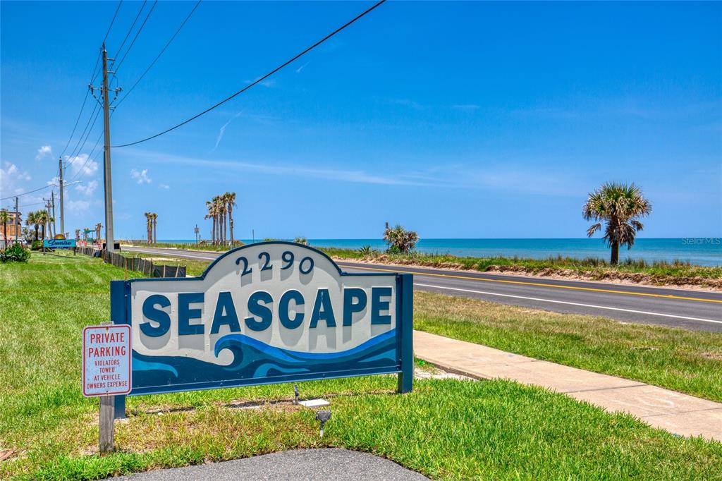 A sign for Seascape stands in a grassy area next to a road and ocean — 2290 OCEAN SHORE BOULEVARD UNIT 2070, ORMOND BEACH, FL