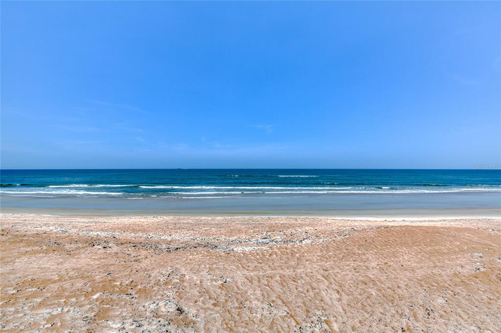 A wide, sandy beach meets the blue ocean under a clear, bright sky — 2290 OCEAN SHORE BOULEVARD UNIT 2070, ORMOND BEACH, FL