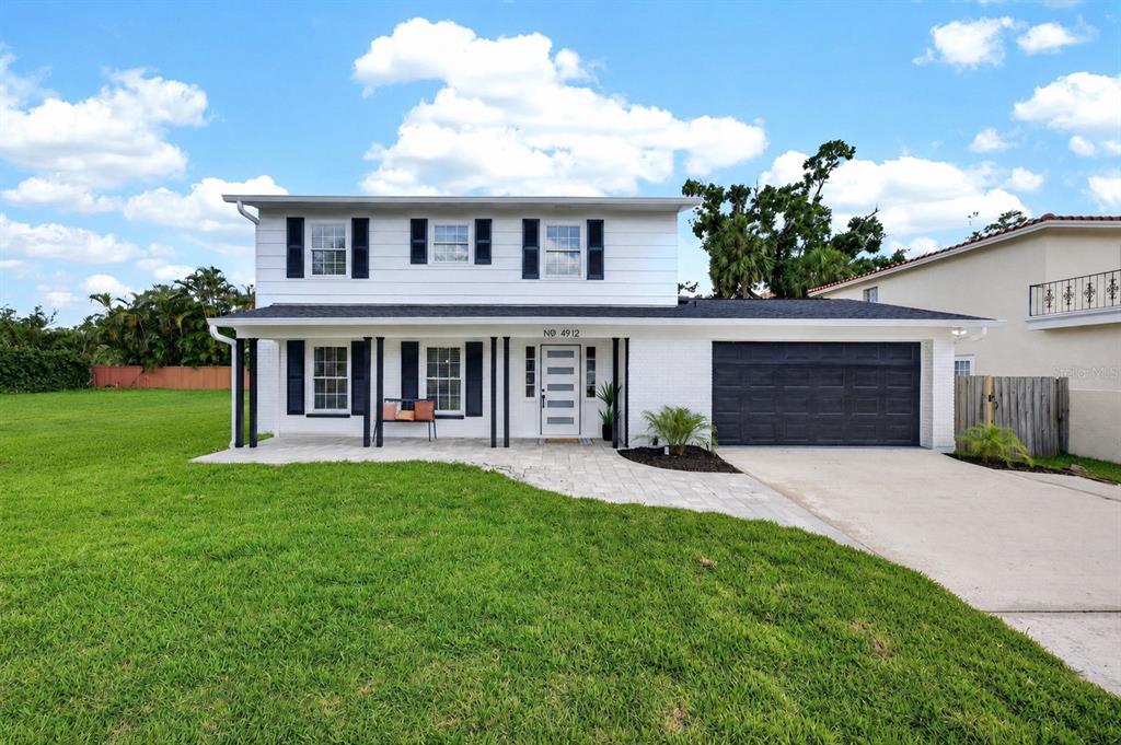 A two-story white house with black shutters and a single-car garage sits on a lawn — 4912 W DRYAD STREET, TAMPA, FL