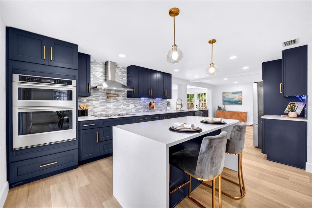 A modern kitchen features navy blue cabinets, a white quartz island, and stainless steel appliances — 4912 W DRYAD STREET, TAMPA, FL