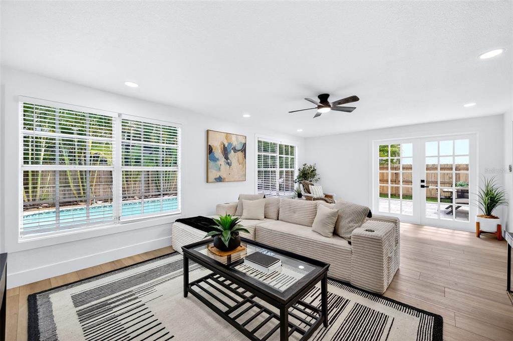 A living room features a sectional sofa, coffee table, area rug, and pool view — 4912 W DRYAD STREET, TAMPA, FL