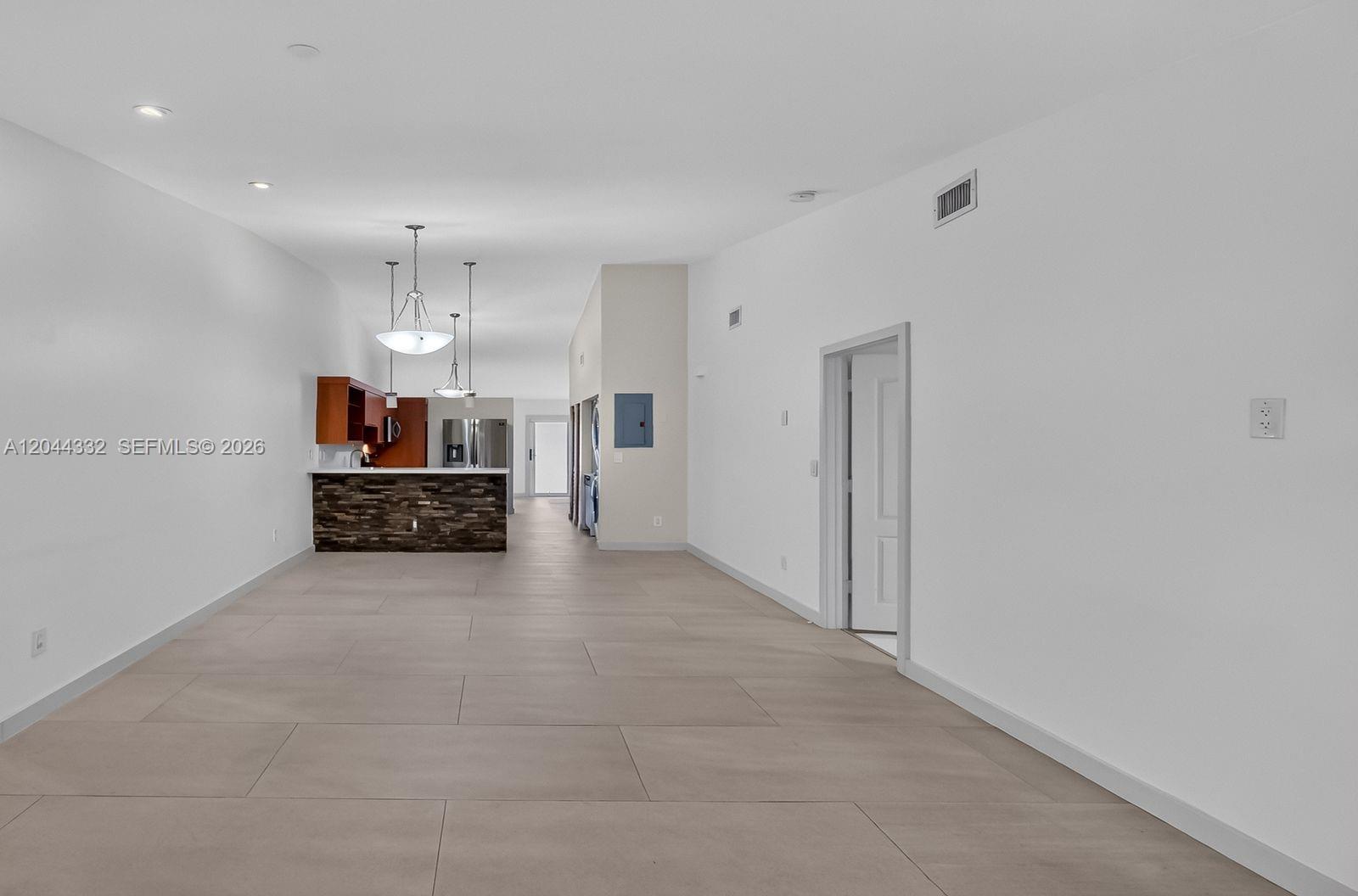 An empty room features white walls, large light-colored floor tiles, a window, and a door — 2141 W 53rd St # 1, Hialeah FL 33016, HIALEAH, FL