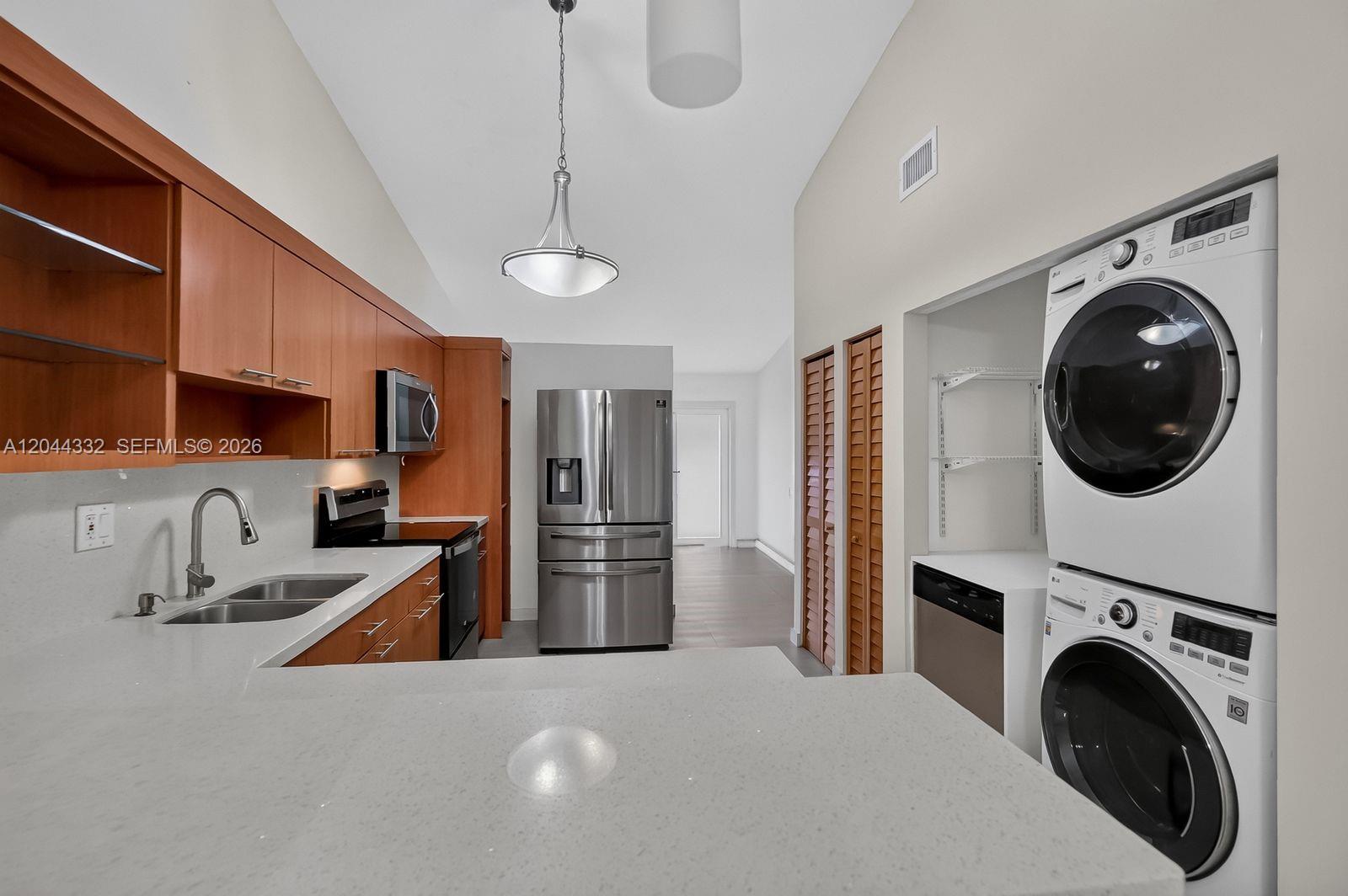 An open-concept living area features light tile flooring, white walls, and a kitchen with a stone-accented island — 2141 W 53rd St # 1, Hialeah FL 33016, HIALEAH, FL