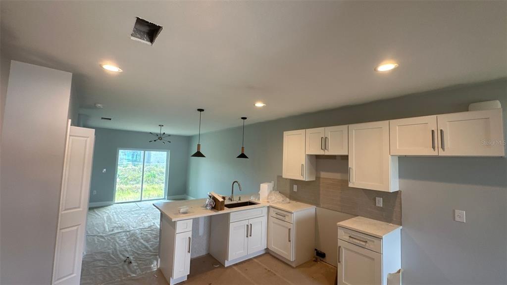 A kitchen with white cabinets, a peninsula, and recessed lighting opens to a living area — 12231 KIRK AVENUE UNIT 2, PORT CHARLOTTE, FL