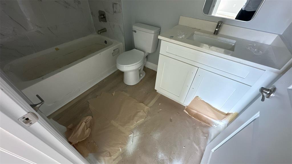 A bathroom features a white vanity, a toilet, and a bathtub with marble-look tile — 12231 KIRK AVENUE UNIT 2, PORT CHARLOTTE, FL