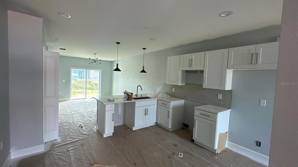 A kitchen with white cabinets and a center island overlooks an unfinished living area — 12231 KIRK AVENUE UNIT 2, PORT CHARLOTTE, FL