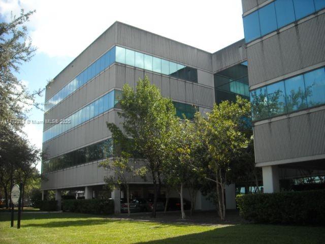 A multi-story office building with a glass facade stands above a ground-level parking area — 14411 Commerce Way # 310, Miami Lakes FL 33016, MIAMI LAKES, FL