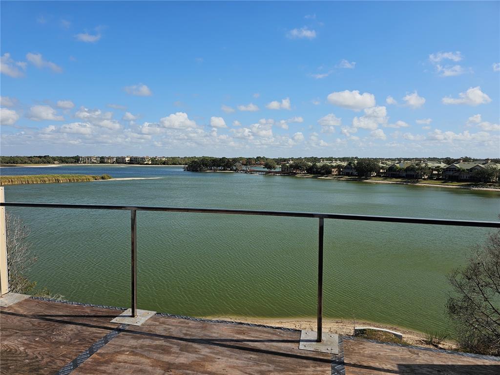 A balcony with a metal railing overlooks a large lake and distant residential buildings — 10775 RODEO DRIVE UNIT Model, LAKEWOOD RANCH, FL