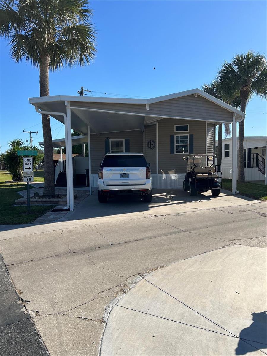 A single-story manufactured home features a carport, a white SUV, and a golf cart — 6601 SE 51st Street, Okeechobee FL 34974, OKEECHOBEE, FL
