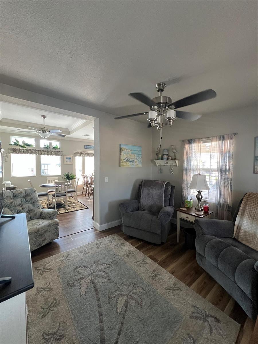 A living room with gray recliners, a palm tree rug, and an adjacent dining area — 6601 SE 51st Street, Okeechobee FL 34974, OKEECHOBEE, FL