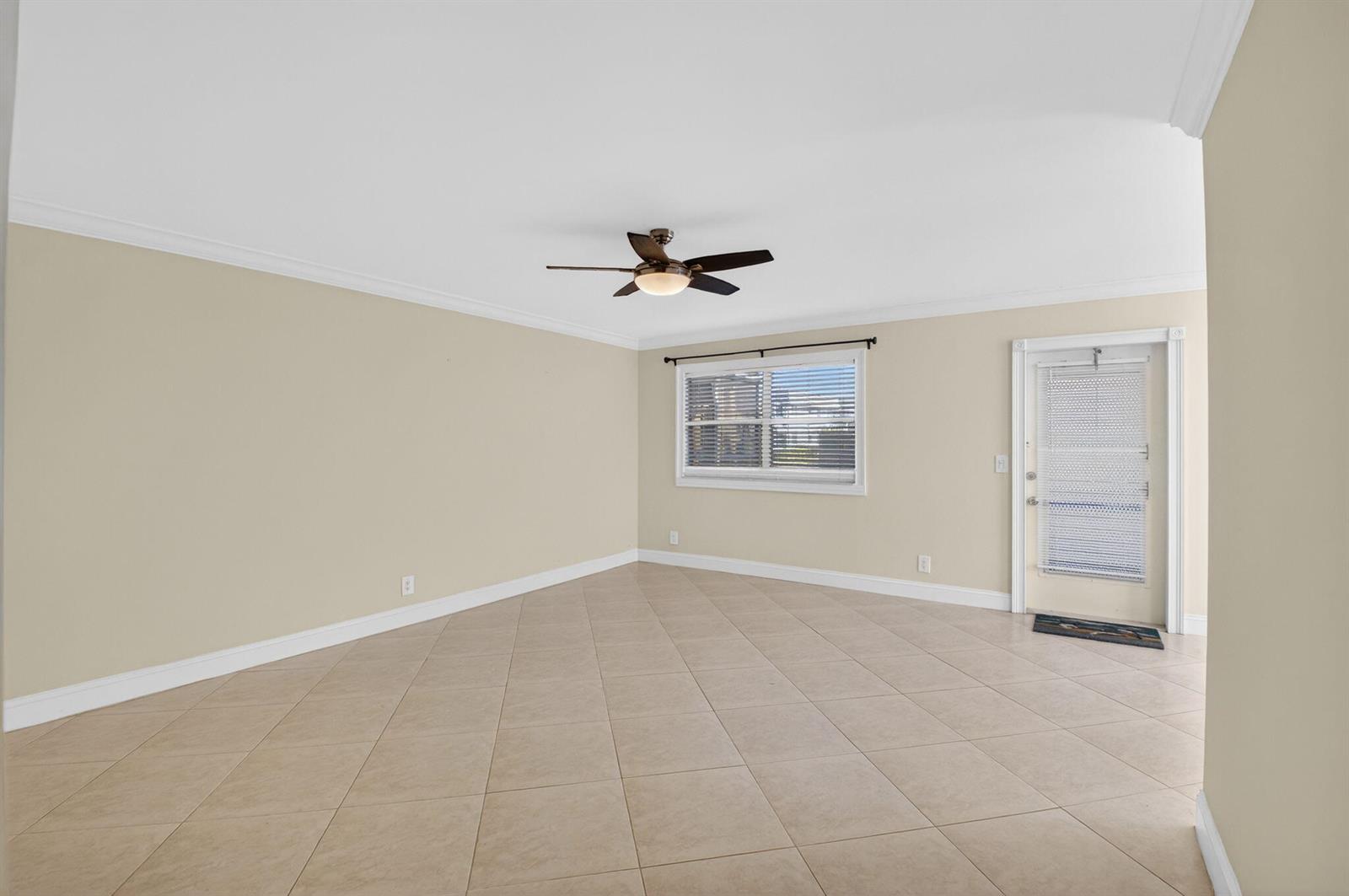 An empty room features beige tile flooring, light-colored walls, a ceiling fan, and a glass-paneled door — 109 Monaco C # 109, Delray Beach FL 33446, DELRAY BEACH, FL