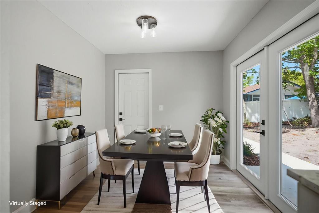 A dining room with a dark table, upholstered chairs, a sideboard, and glass patio doors — 7407 DUNDEE WAY, WEEKI WACHEE, FL